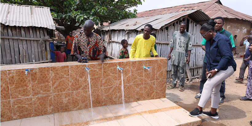Nigerian Breweries Plc Corporate Affairs Director, Sade Morgan, inspecting the pure water source donated to the Olokemeji community, alongside some Olokemeji residents.
