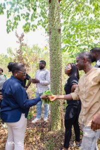 Sade Morgan receiving leaves of Ceiba Pentandra to try as food, from Adewale Awoyemi, IITA Forest Center Manager, under the canopy of one of the fastest growing trees of the Olokemeji Reforestation Project.