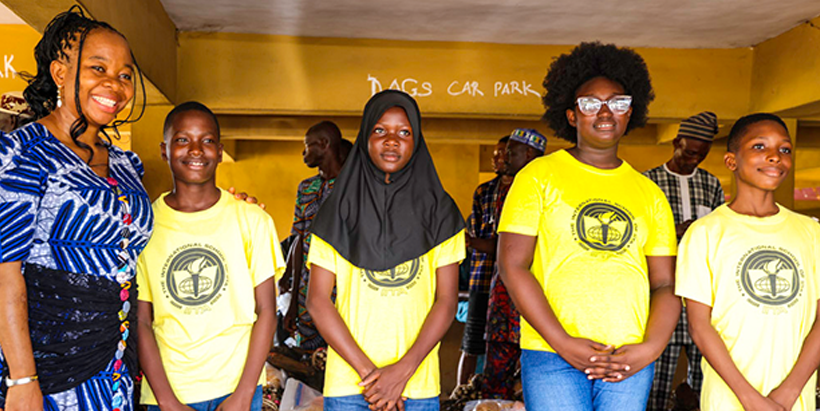 Joshua Ayankanmi standing by his proud mentor, Oluchi Odom-Kolombia, and his classmates after distributing the improved cassava, maize, and plantain varieties to farmers.