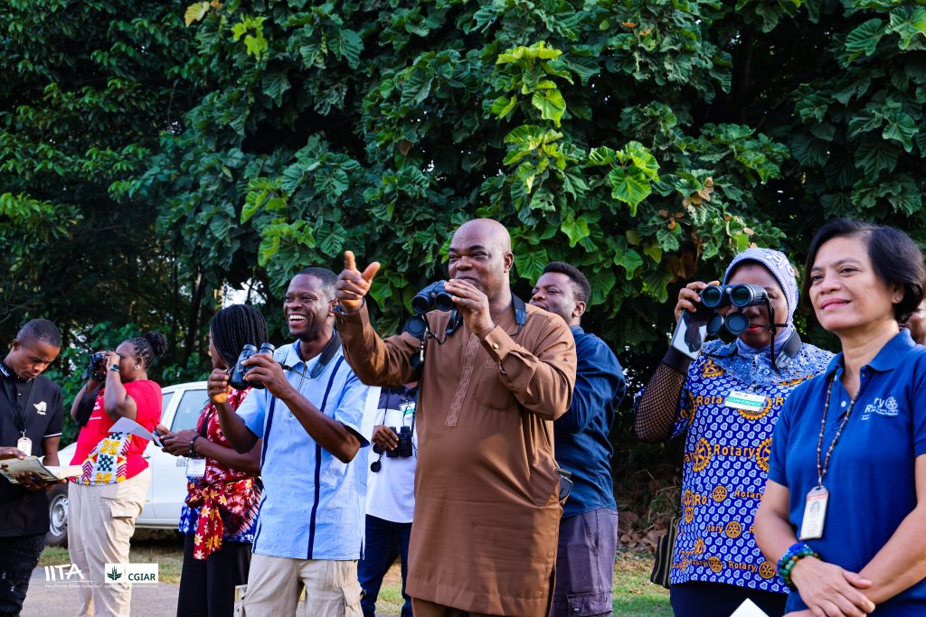Rotarian Incoming President Elect (RIPE), Olayinka Babalola sights the pied kingfisher with his binoculars during the birdwatching exercise, guided by the Head of IITA Forest Center, Adewale Awoyemi, in the company of other Rotarians, the Head of Communication, Kathy Lopez and IITA staff.